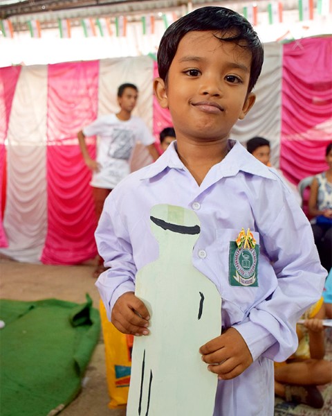 Young boy in community center, holding cardboard
