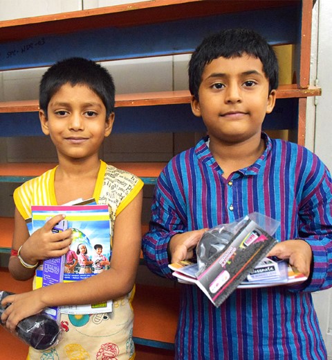 Debayan and Pramit holding coloring books and other gifts