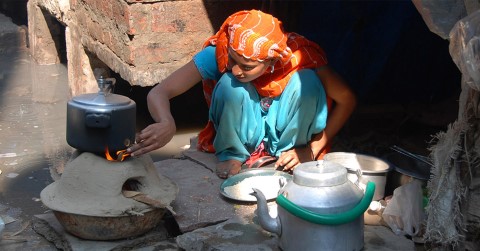 a woman in a blue dress cooking food on a stove