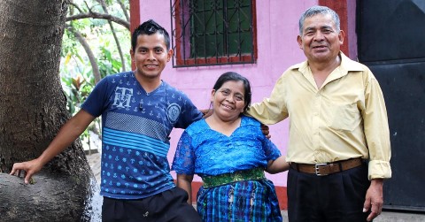 a youth with his parents standing by a tree