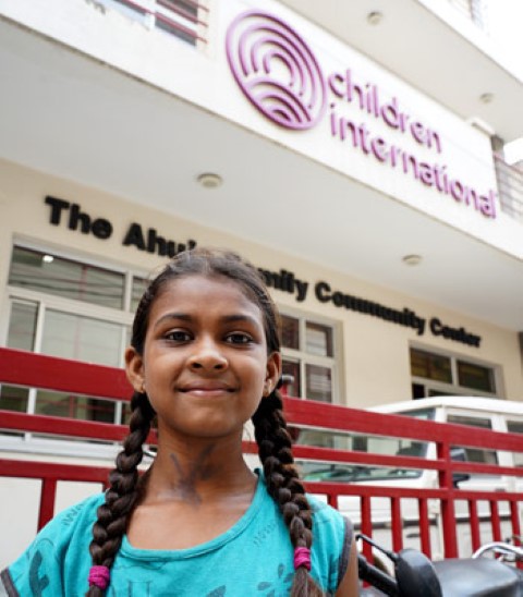 a little girl standing in front of a building