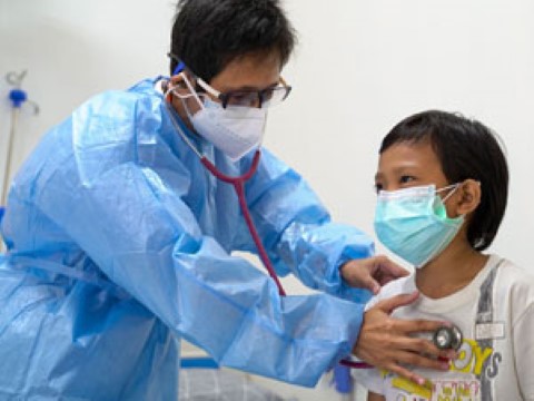 un hombre con una bata de hospital le está poniendo un estetoscopio a un niño