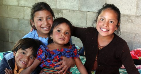 a group of children sitting on top of a bed