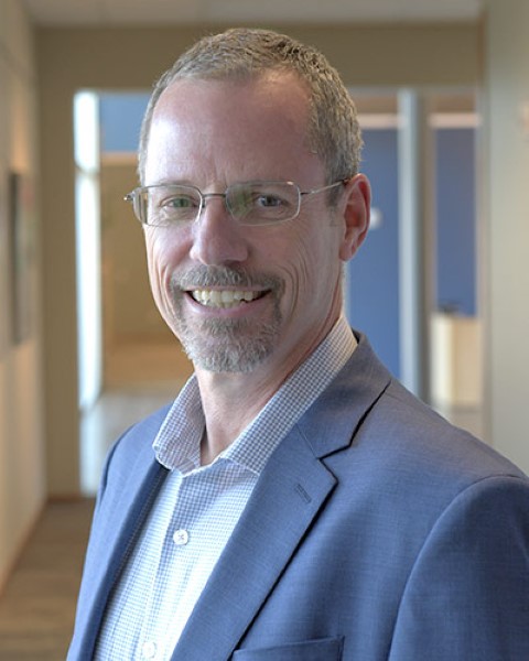 a man in a suit and glasses standing in a hallway