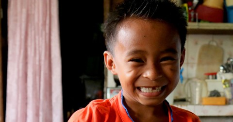 A young boy’s smile reveals a missing front tooth