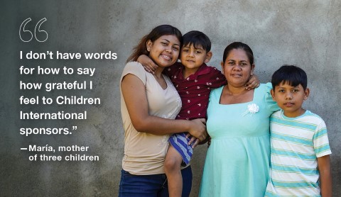 Maria and her children smiling outside of their home