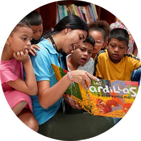 a woman reading a book to a group of children