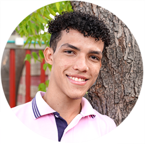 a young man standing next to a tree