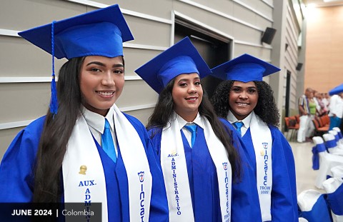 Girls in caps and gowns smile on graduation day