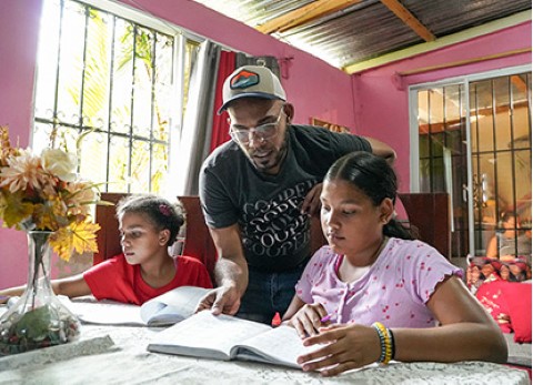 a man helping two girls with homework