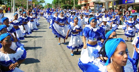a group of children dressed in traditional costumes dancing in the street.
