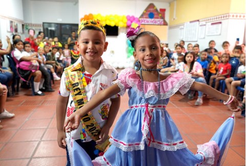 two little children dressed in traditional costumes smiling at the camera
