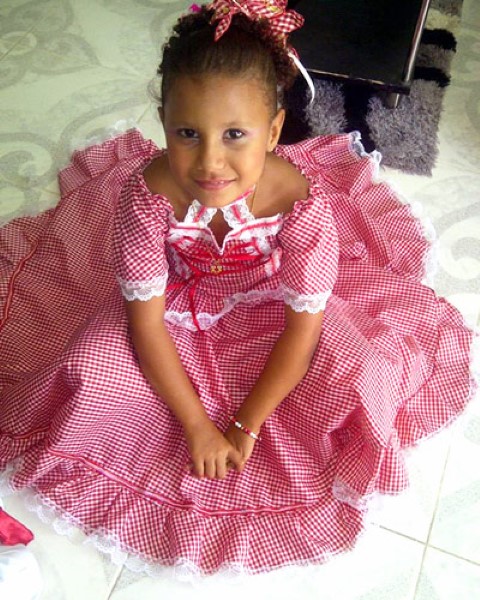 a girl in a typical costume sitting on the floor smiling at the camera.