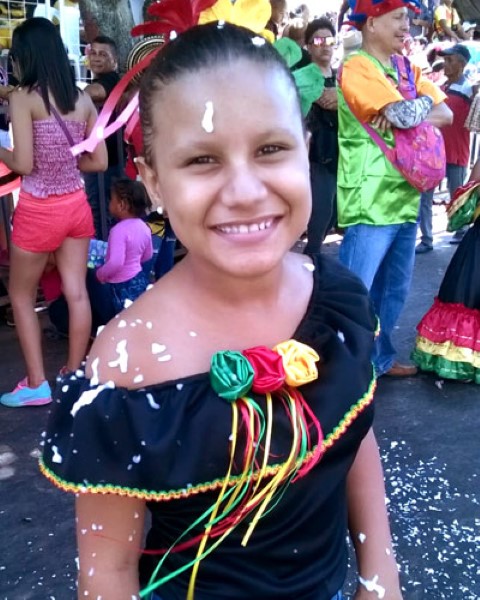 a young teen with a typical costume in the middle of a carnival parade 