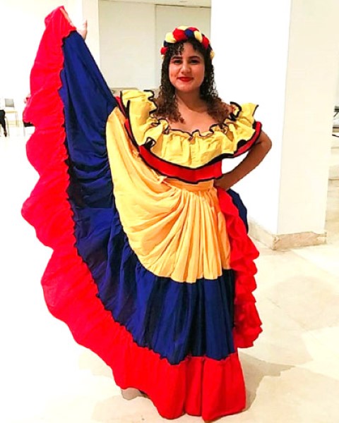 a young girl dressed in typical Colombian costume smiling at the camera